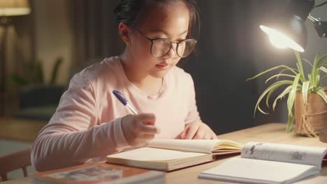asian child doing homework at night, asia child writing on book