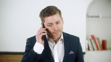 a frustrated young businessman is talking his phone