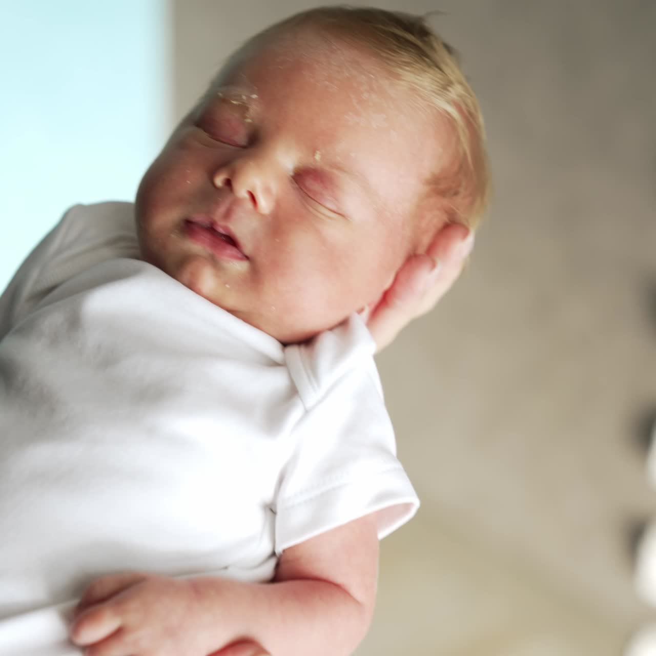 Little baby in white bodysuit peacefully sleeping on parent's hand. Father's finger is touching tiny kid's nose. Close up