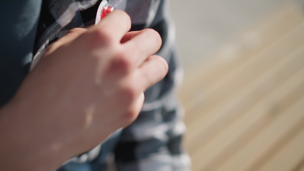 close up of man wearing checkered shirt pulling out pill from shirt pocket during sunny day with soft shadows and blurred wooden bench in background