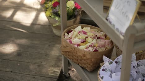 basket filled with rose petals and paper cones on a rustic wooden stand for wedding guests
