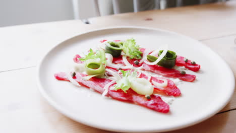 Close-up-shot-of-salmon-and-garnishing-on-a-white-plate-served-in-a-restaurant,-selective-focus