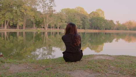 woman sitting by a lake in a park