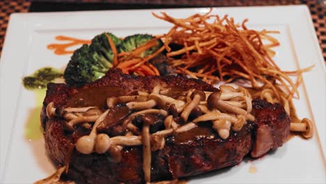 close up angus steak with mushroom sauce on a white plate