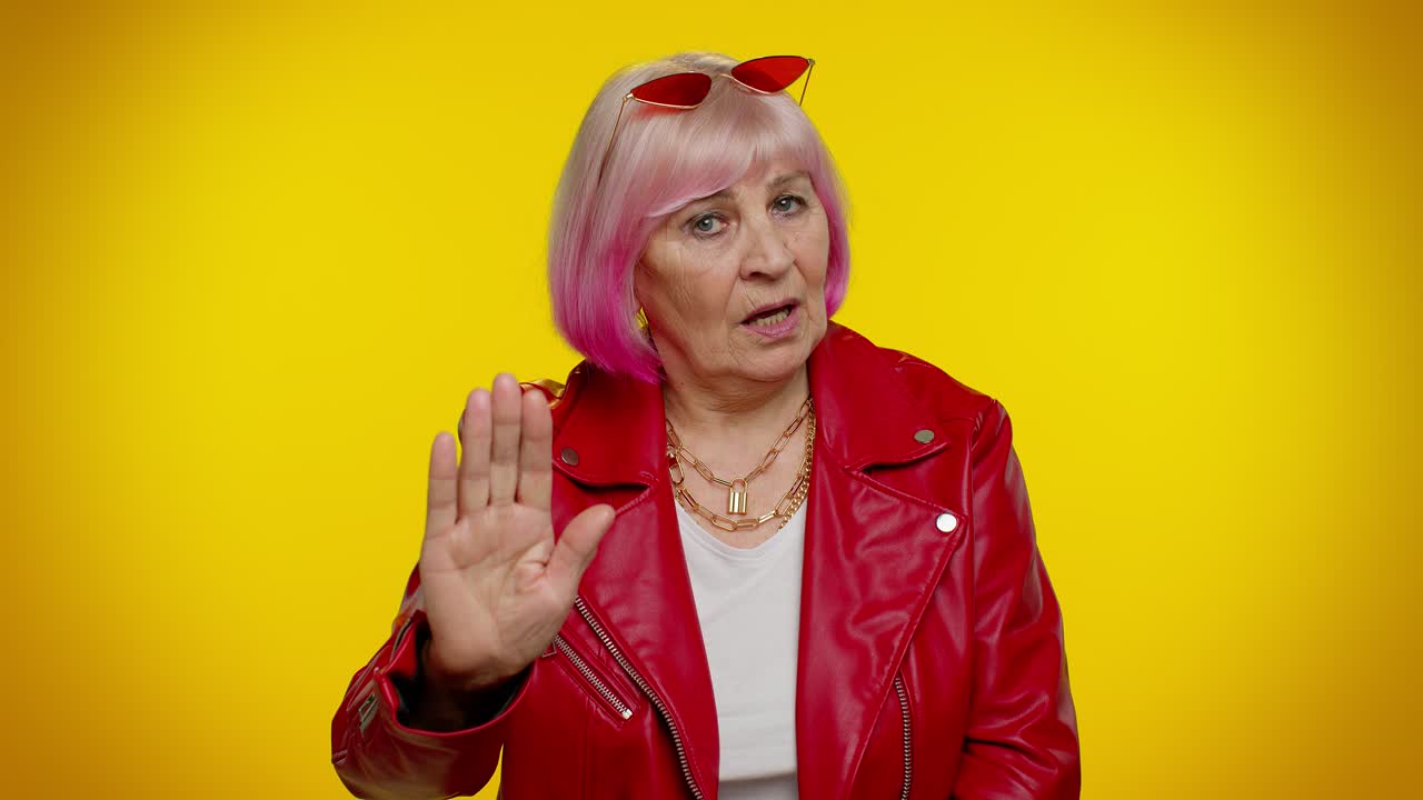 una mujer con una chaqueta roja y cabello rosa haciendo un gesto de señal de parada