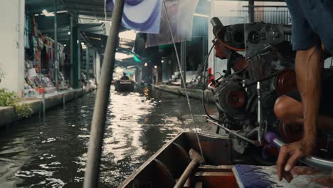 traditional long tail boat driver manually controlling and steering the watercraft through a narrow waterway