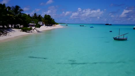aerial rise over quiet maldives island with traditional dhoni sailboats moored in brilliant lagoon, 4k