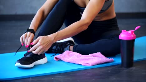 Woman tying her shoes on yoga mat