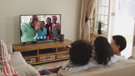 Afroamerikanische-Familie,-Die-Einen-Videoanruf-Im-Fernsehen-Führt,-Während-Sie-Zu-Hause-Auf-Der-Couch-Sitzt