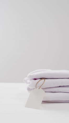 vertical video of stack of folded white t shirts with copy space on white background