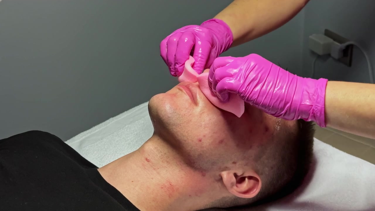 Uomo che riceve un trattamento viso in un centro estetico nel pomeriggio, con un'estetista che applica una maschera.