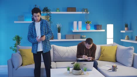 el hermano menor molestando a su hermano mayor que está estudiando.