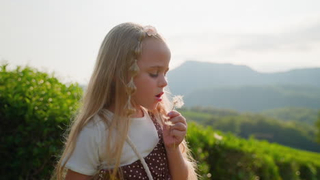niña pequeña soplando un diente de león en una plantación de té