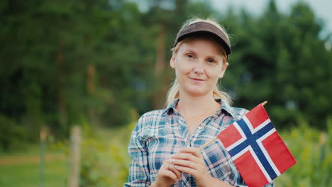 a woman with the flag of norway stands against a garden norwegian farmers