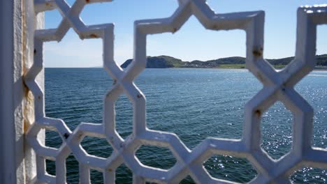 north wales green mountain island coastline through ornate patterned wrought iron railing jib up left