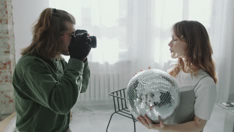 photographer taking photos of beautiful model posing with disco ball