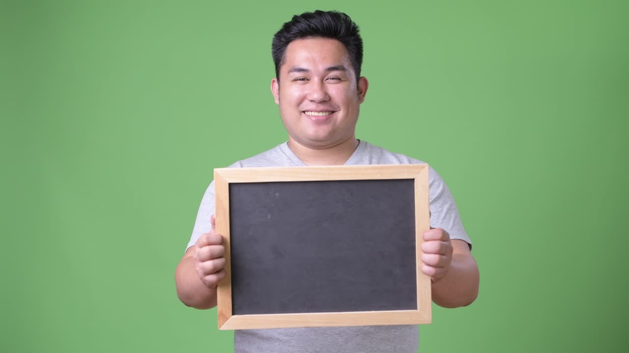 초록색 배경에 젊은 잘생긴 과체중 아시아인