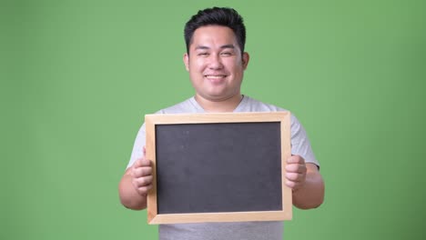 초록색 배경에 젊은 잘생긴 과체중 아시아인