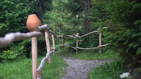 Traditional-clay-pitcher-jug-on-log-in-the-yard-of-house-with-a-rustic-wooden-fence-background-Old-ceramic-pot