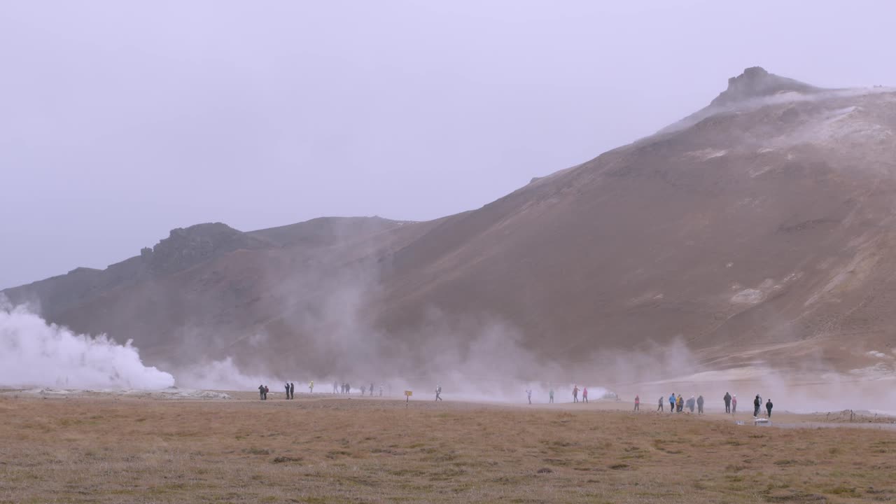 Tourists explore the misty geothermal landscape at Namaskaro hot springs in Iceland