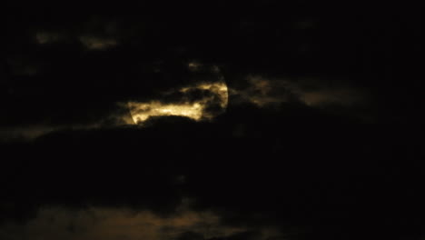 mystic light coming through behind dramatic clouds during full moon at night, static shot