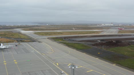 distant airplane landing on airport runway in iceland on grey cloudy day, aerial