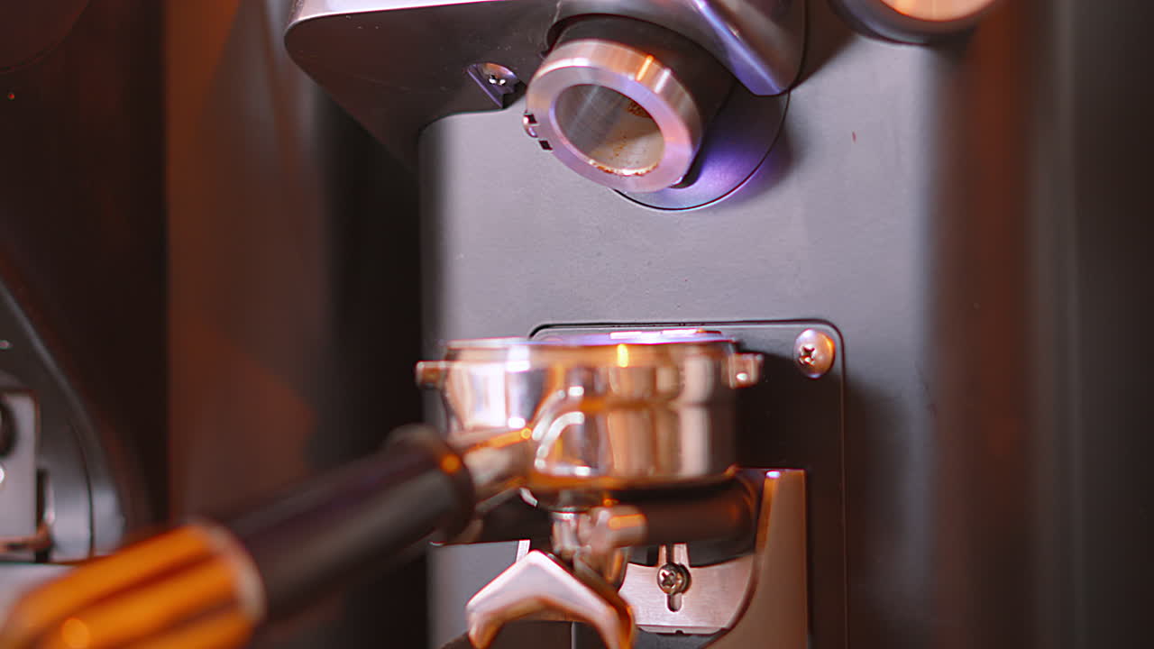 Macinacaffè con portafiltro e chicchi macinati che si svuotano lentamente. Clip di una caffetteria locale indipendente. Preparazione di una bevanda calda.