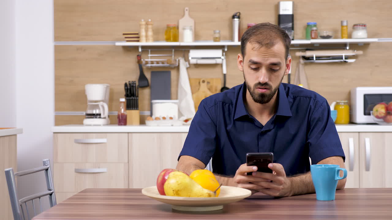 hombre usando un teléfono inteligente en la cocina