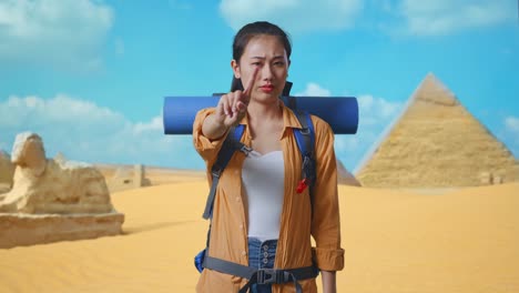 asian female hiker with mountaineering backpack showing no gesture with index finger while traveling in pyramid of giza