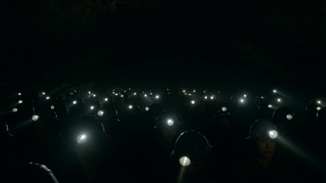 Group of miners with headlamps in a dark underground environment