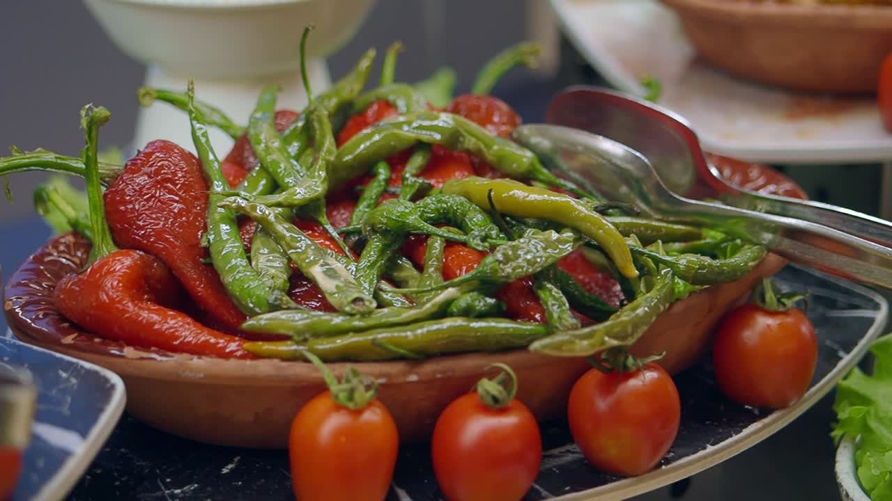 Livlige grønne og røde chilier med tomater i en skål.