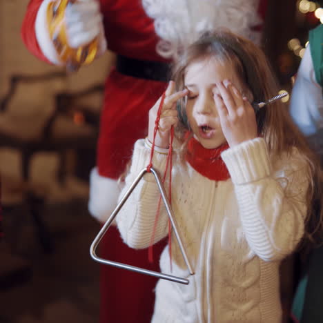 beautiful little girl singing and dancing with santa and elf. happy children spend great time at christmas indoors. close-up.