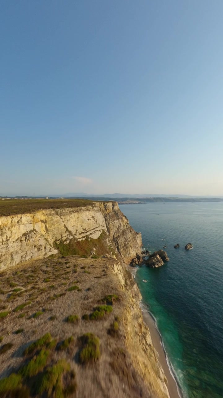 Volo verticale cinematografico di drone sopra le aspre scogliere calcaree di Cabo Peñas, il punto più settentrionale delle Asturie, Spagna, che si affaccia sul blu del Mar Cantabrico.