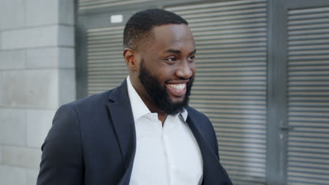 African-businessman-walking-on-city-street.-Smiling-business-man-going-outdoors