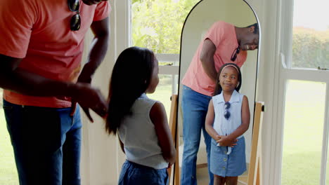 african american, father brushing daughter's hair at home, both smiling in front of mirror