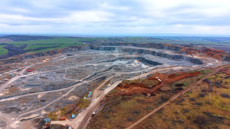 Quarry site shows earth removal. Aerial view of a large quarry showing heavy machinery and trucks working to remove earth