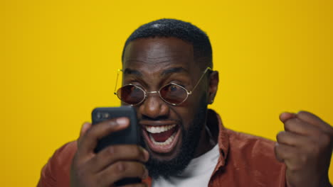 closeup surprised african man celebrating victory on yellow background.