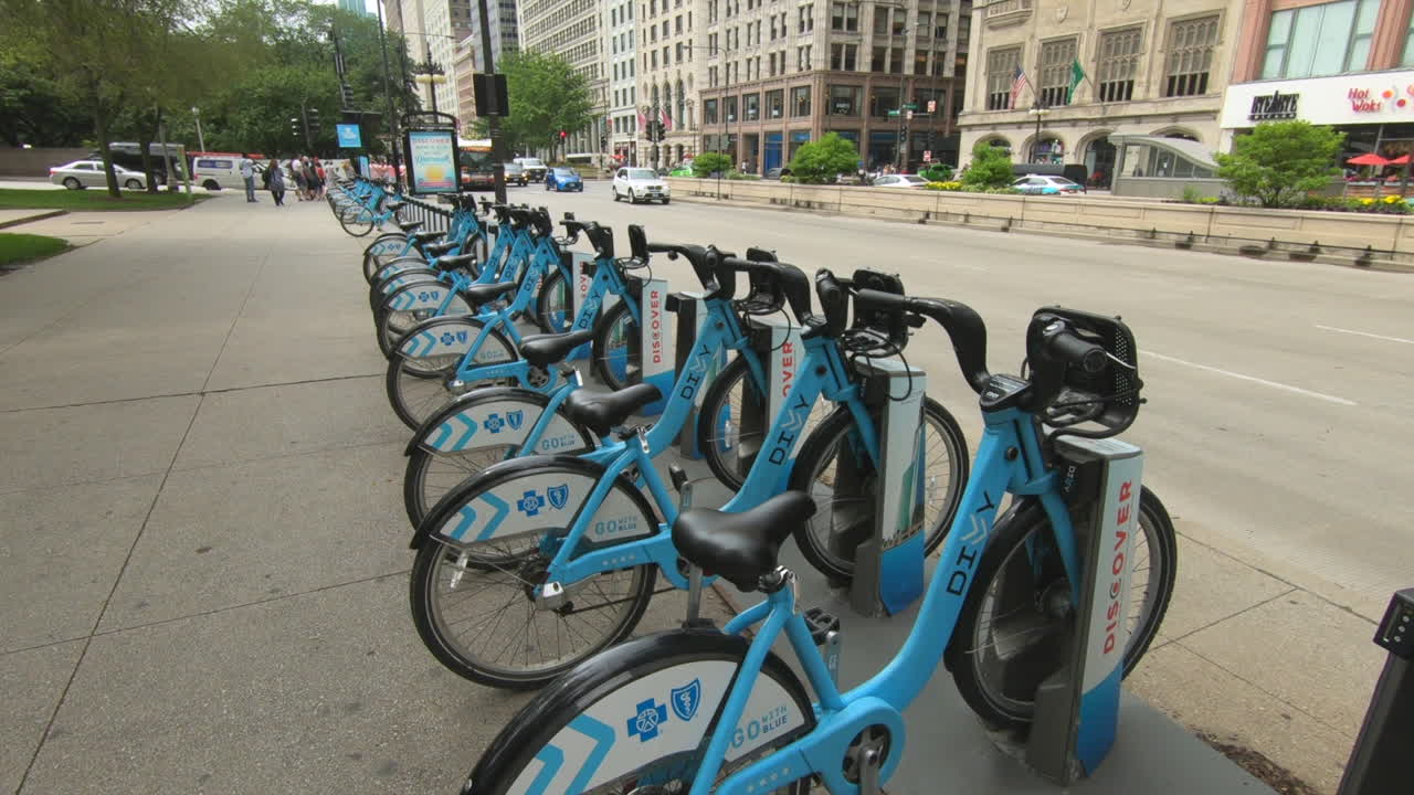 Editorial, Chicago public bike share station, diyy, divvy, blue bicycles, street view, buildings, people and cars passing.