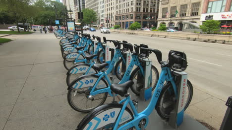 editorial, chicago public bike share station, diyy, divvy, blue bicycles, street view, buildings, people and cars passing.