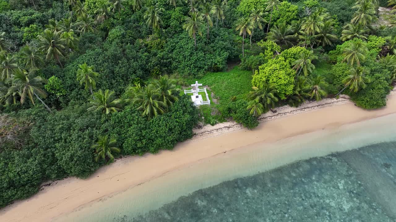 White cross memorial in remote island, drone reveal tropical coastal scenery of Tonga, Pacific.