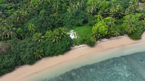 white cross memorial in remote island, drone reveal tropical coastal scenery of tonga, pacific.