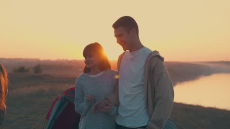 lovely couple joins hands near tent and friends in camp