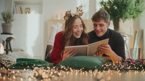 pareja con álbum de fotos acostado en la sala de estar