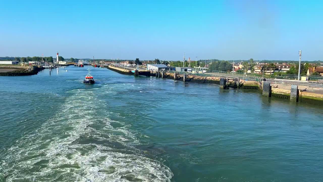 Ship leaving harbour with wake and road with cars on one side