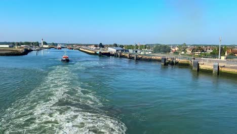 ship leaving harbour with wake and road with cars on one side