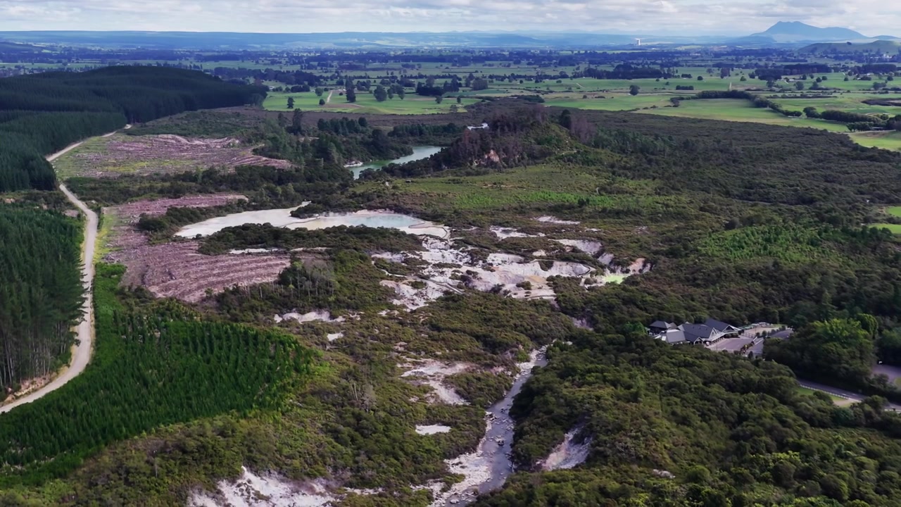 Rotorua, Nova Zelândia, vasta área geotérmica, vegetação nativa, plantações florestais e cursos d'água termais em paisagem vulcânica na Ilha Norte.
