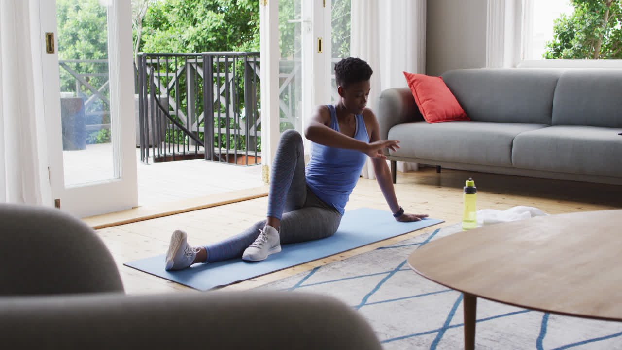 African american woman performing stretching exercise at home