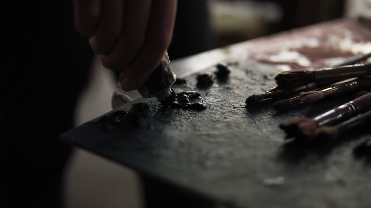 팔레트에 페인트를 뿌리는 손의 영상입니다.