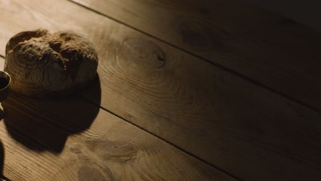 religious concept shot with chalice bread and wine on wooden table with pool of light 3