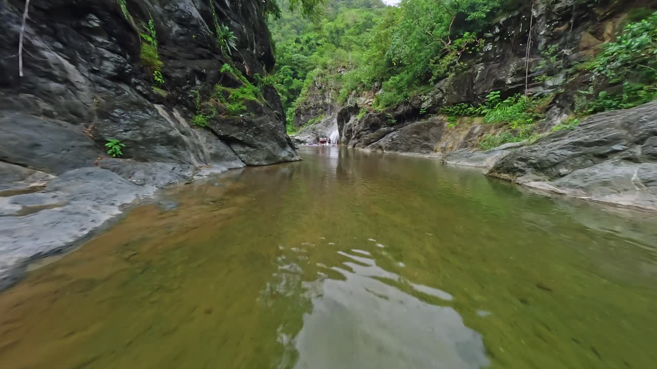 vuelo de drones de velocidad fpv sobre un río natural claro en la jungla de la república dominicana